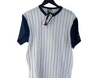 May include: A white and blue striped short-sleeved shirt with a black collar and black sleeves. The shirt has a button closure and a tag that says "Bike" on it.