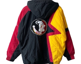 Puede incluir: Chaqueta con capucha negra, roja y amarilla con un logotipo de los Florida State Seminoles en la espalda. La chaqueta tiene una cremallera y una capucha con cordón.