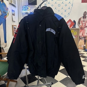 May include: Black North Carolina jacket with blue hood detailing. The jacket features a button-up front and the words "North Carolina" are embroidered across the chest. The Starter logo is visible on the sleeve.