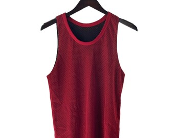 May include: A red mesh tank top hanging on a black hanger. The tank top has a black mesh lining.