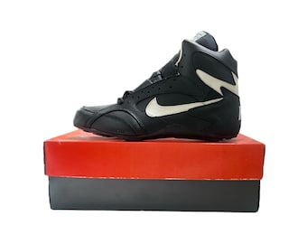 May include: Black leather high-top sneakers with a white Nike swoosh logo and a white accent on the side. The shoes are sitting on a red box.
