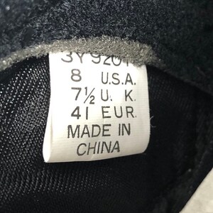 Puede incluir: Una etiqueta blanca con texto negro que indica las tallas de zapatos en tallas US, UK y EU. La etiqueta dice "8 U.S.A. 7 1/2 U.K. 41 EUR. MADE IN CHINA."