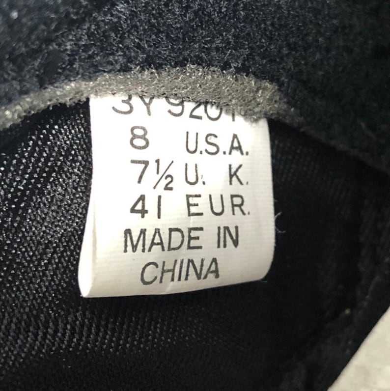 Puede incluir: Una etiqueta blanca con texto negro que indica las tallas de zapatos en tallas US, UK y EU. La etiqueta dice "8 U.S.A. 7 1/2 U.K. 41 EUR. MADE IN CHINA."