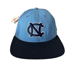 Könnte beinhalten: Hellblaue Baseballkappe mit marineblauem Schirm. Die Kappe hat ein marineblaues, gesticktes Logo auf der Vorderseite. Ein Etikett ist an der Seite befestigt.