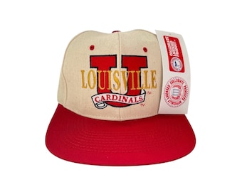 May include: A beige and red baseball cap with the text "Louisville Cardinals" and a large red "U" embroidered on the front.