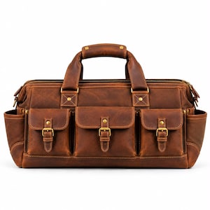 May include: A brown leather duffel bag featuring two top handles, a main zippered compartment, and three front pockets with buckle closures. The bag includes two side pockets and is accented with brass-toned metal hardware and rivets.