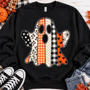 May include: A black long-sleeve sweatshirt featuring a large central ghost graphic. The ghost is composed of vertical patchwork panels with various patterns including orange gingham, black and white polka dots, floral prints, and black heart motifs.