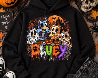 Puede incluir: Una sudadera negra con capucha que presenta un gráfico colorido de cuatro perros de dibujos animados vestidos con disfraces de Halloween, incluyendo un fantasma, un zombi y una momia. El texto "BLUEY" aparece en una fuente multicolor.
