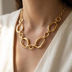 Puede incluir: Un collar de cadena en tono dorado que presenta una serie de eslabones pulidos alternos, incluyendo formas ovaladas irregulares y suaves junto a conectores hexagonales más pequeños y estructurados, creando un diseño metálico continuo.