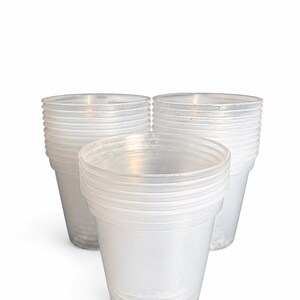 May include: Three stacks of clear, disposable plastic cups arranged in a triangular formation. Each stack consists of multiple translucent, lightweight drinking vessels with a smooth, tapered design and a simple, circular rim at the top.