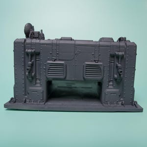 May include: A dark gray 3D printed miniature structure featuring a rectangular base, vertical wall panels with rivets, two rectangular vents, and a small satellite dish mounted on the top left corner. The structure has a hollow arched opening.