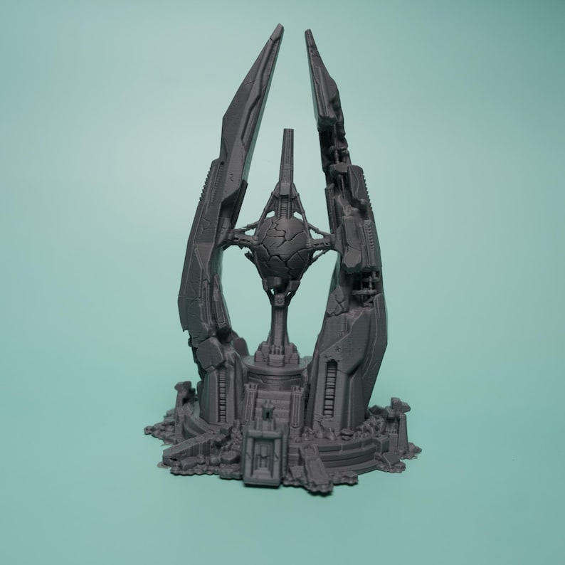 K&ouml;nnte beinhalten: Eine graue 3D-gedruckte Skulptur mit einer zentralen, rissigen Kugel, die in einem komplexen mechanischen Rahmen h&auml;ngt. Die Struktur umfasst zwei hohe, spitze vertikale S&auml;ulen, die den Kern flankieren, auf einer detaillierten Basis.