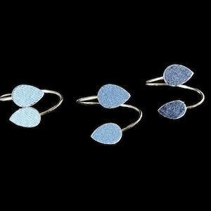 May include: Three silver rings with blue teardrop-shaped embellishments. The rings are twisted and have a delicate design.