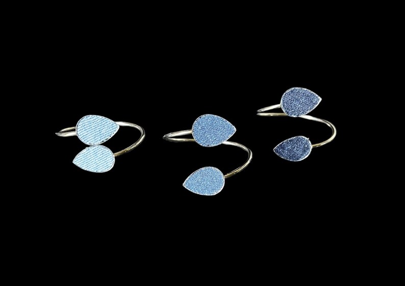 May include: Three silver rings with blue teardrop-shaped embellishments. The rings are twisted and have a delicate design.