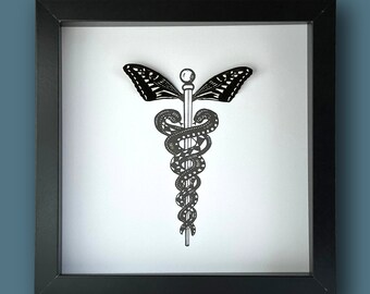 Pode incluir: Uma impressão emoldurada em preto e branco de um símbolo de caduceu médico com asas de borboleta. O caduceu é um cajado com duas cobras entrelaçadas ao redor, e as asas estão abertas de ambos os lados.