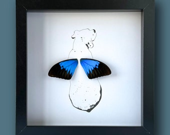 Pode incluir: Uma imagem emoldurada em preto com fundo branco. Uma borboleta azul com marcas pretas está montada no centro da moldura. A borboleta está espalhada com as asas abertas. A borboleta está centrada em um desenho de linha simples de um cão.