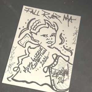 Può includere: Una carta rettangolare bianca con un disegno a inchiostro nero di una persona che tiene un'ascia. Il testo recita FALL RIVER MA, MISS LIZZIE BORDEN, 2026, e altri segni stilizzati. L'illustrazione raffigura una figura con una fascia.