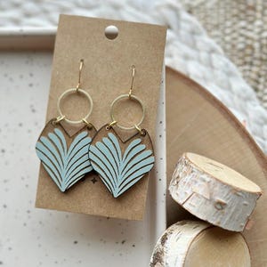 May include: A pair of light blue wooden earrings with a fan-shaped design. The earrings have gold hoops and hooks.