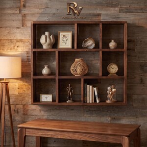 May include: A dark brown wooden wall shelf with multiple rectangular compartments. The shelves hold a textured white vase, a framed floral print, a geode, a small vase, a woven basket, a clock, a figurine, books, and a glass cloche with dried flowers.