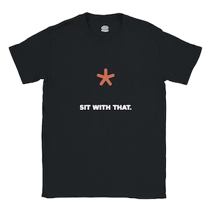 Op de afbeelding: Een zwart t-shirt met korte mouwen voorzien van een klein oranje asterisk-symbool boven de witte tekst SIT WITH THAT. Het shirt bevat een klein rond merklogo dat aan de binnenkant van de kraag is gedrukt.