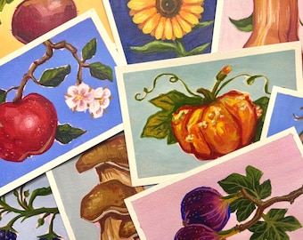 May include: A collection of rectangular art prints featuring various botanical illustrations, including a red apple on a branch, a bright orange pumpkin, a yellow sunflower, brown mushrooms, and dark purple figs on a light pink background.