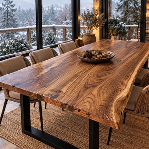 May include: A large rectangular dining table featuring a natural live edge wood slab top with prominent grain patterns, supported by two black metal U-shaped legs. A shallow circular bowl containing pinecones sits in the center.