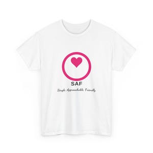 May include: A white short-sleeved t-shirt featuring a pink circle with a pink heart inside. Below the circle, the text reads SAF, followed by the text Single. Approachable. Friendly. in a black script font.