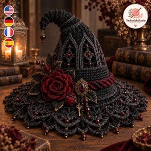May include: A black crocheted pointed hat featuring a wide, scalloped brim adorned with dark red beads. The hat is decorated with a large dark red crocheted rose, a central oval brooch with a red stone, and a small dangling gold-coloured key charm.