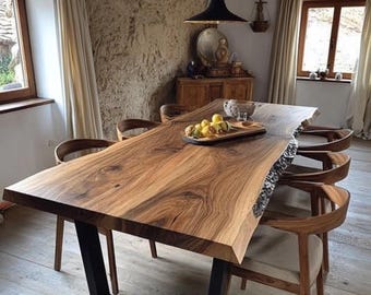Puede incluir: Una mesa de comedor rectangular con un tablero de madera de borde natural con vetas pronunciadas, sostenida por dos patas de metal negro en forma de U. La mesa está rodeada por seis sillas de madera con respaldos curvos y cojines de asiento claros.