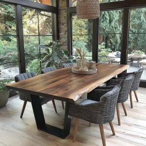 Puede incluir: Una mesa de comedor rectangular con tablero de madera oscura de borde natural y base de metal negro en forma de U. Seis sillas trenzadas grises con patas de madera clara est&aacute;n dispuestas alrededor. Una bandeja trenzada sostiene jarrones.