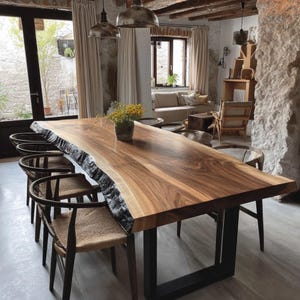 Peut inclure: Une grande table à manger rectangulaire dotée d'un plateau en bois massif à bord naturel avec un grain brun riche, soutenue par deux pieds en métal noir en forme de U. La table est entourée de plusieurs chaises en bois foncé à assise tressée.