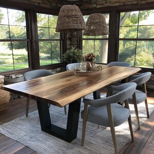Puede incluir: Una mesa de comedor rectangular de madera con borde natural, veteado visible y acabado marr&oacute;n oscuro, sostenida por dos patas de metal negro en forma de U. La mesa est&aacute; rodeada por cuatro sillas tapizadas en gris claro con patas de madera.