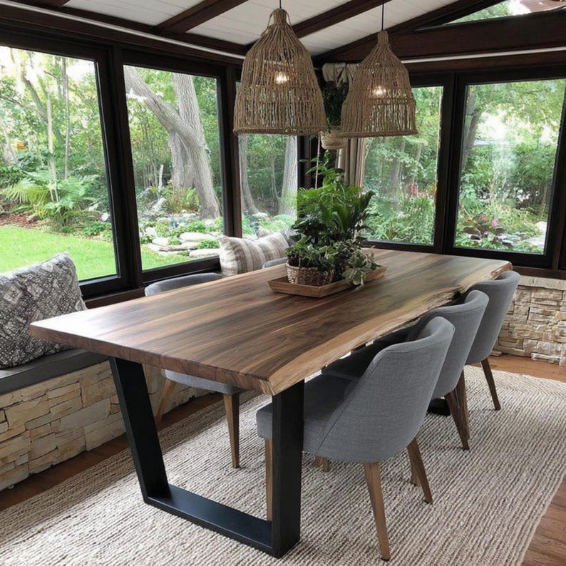 Puede incluir: Una mesa de comedor de madera con borde natural, veta marr&oacute;n oscura y patas de metal negro en forma de U. La mesa est&aacute; rodeada por cuatro sillas tapizadas en gris con patas de madera y dos l&aacute;mparas colgantes de cuerda trenzada.