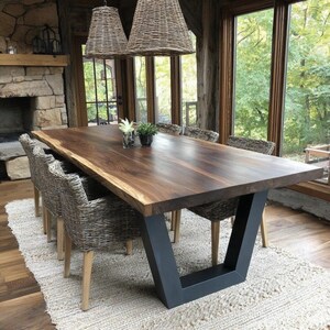 Puede incluir: Una mesa de comedor rectangular con un tablero de madera marr&oacute;n oscuro de borde natural y una base trapezoidal de metal negro, acompa&ntilde;ada de seis sillas de mimbre trenzado con patas de madera clara sobre una alfombra de color crema.