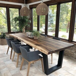 Puede incluir: Una mesa de comedor rectangular con una superficie de madera de borde natural y una base de metal negro en forma de U. La mesa est&aacute; rodeada por cuatro sillones tapizados en gris oscuro con patas de madera clara. Dos l&aacute;mparas colgantes tejidas.