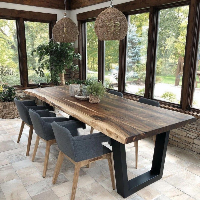 Puede incluir: Una mesa de comedor rectangular con una superficie de madera de borde natural y una base de metal negro en forma de U. La mesa est&aacute; rodeada por cuatro sillones tapizados en gris oscuro con patas de madera clara. Dos l&aacute;mparas colgantes tejidas.