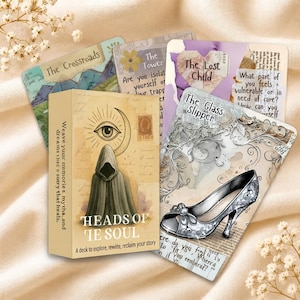 Op de afbeelding: Een set orakelkaarten getiteld Heads of the Soul, bestaande uit een doos met een afbeelding van een figuur met een kap en een oog. De kaarten tonen diverse ontwerpen waaronder The Crossroads, The Tower, The Lost Child en The Glass Slipper met tekst.