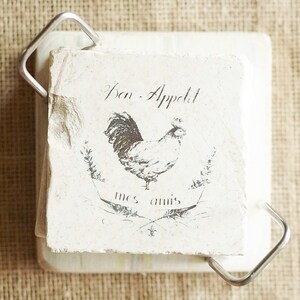 May include: A white square coaster with a black and white image of a rooster and the text "Bon Appetit mes amis".