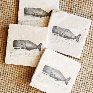 May include: Four square stone coasters with a vintage illustration of a whale on each. The coasters are beige with black ink and have a handwritten inscription on each.