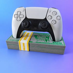 May include: A white and black wireless video game controller resting on a stack of prop money. The money features green graphics with the text Grand Theft Auto and One Hundred Dollars, secured by a yellow band labeled $10,000.