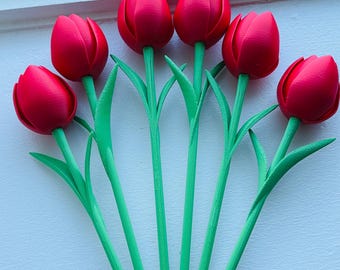 May include: A set of five artificial tulips with vibrant red flower heads and bright green stems and leaves. Each tulip features a smooth, rounded petal structure and a long, slender stalk, arranged in a fan-like formation on a flat surface.