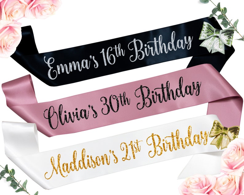 May include: Three satin sashes with different colored backgrounds and gold, silver, or black glitter lettering. The sashes read "Emma's 16th Birthday", "Olivia's 30th Birthday", and "Maddison's 21st Birthday".