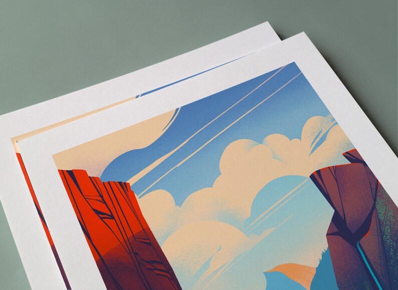 May include: A rectangular art print featuring a stylized landscape illustration with vibrant red rock formations on the left and dark purple cliffs on the right, set against a bright blue sky filled with soft, rounded cream-colored clouds.