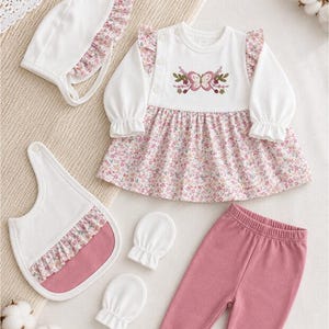 Peut inclure: Un ensemble de vêtements pour bébé comprenant une robe blanche à manches longues avec une jupe à fleurs roses et une broderie papillon, un bonnet assorti à volants, un legging rose uni à pieds, un bavoir blanc à bordure fleurie et deux moufles.