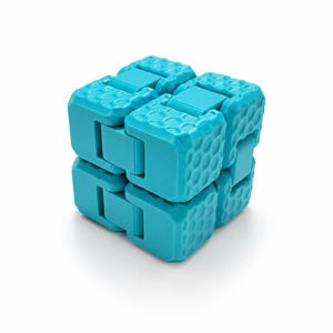 May include: A bright turquoise fidget cube constructed from multiple interconnected plastic segments. Each segment features a distinct hexagonal honeycomb texture on its outer surface, and the cube is shown in a folded, compact configuration.