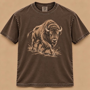 May include: A dark brown short-sleeve t-shirt featuring a detailed graphic illustration of a bison in a tan color. The shirt has a crew neckline and a visible brand label on the inside collar. The fabric has a washed, vintage-style appearance.