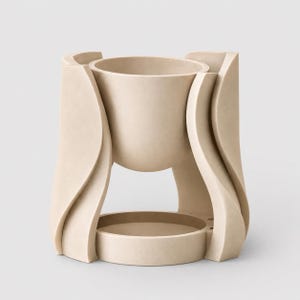 May include: A beige wax warmer featuring a central bowl for wax melts suspended above a circular base. The structure is supported by four curved, wave-like vertical panels that create an open design, providing a clear view of the lower platform.