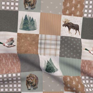 May include: A patchwork quilt fabric featuring a woodland theme with bears, moose, ducks, and trees in shades of brown, green, and gray.