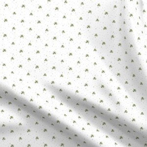 Puede incluir: Tela blanca con un patr&oacute;n repetido de peque&ntilde;os tr&eacute;boles verdes.