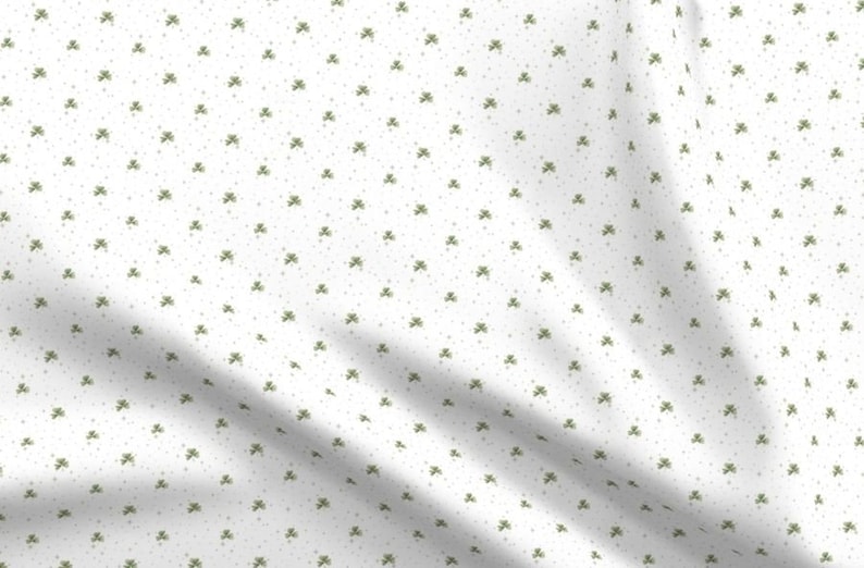 Puede incluir: Tela blanca con un patr&oacute;n repetido de peque&ntilde;os tr&eacute;boles verdes.